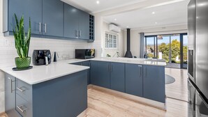 A modern kitchen with a central island, dark blue cabinets, and a view to the outdoors.