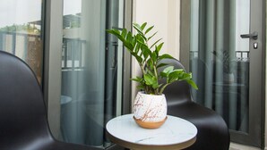 A balcony with two black chairs, a small round table, and a potted plant. - Comfy One Bedroom Apartment @ The Bantree (Accra)