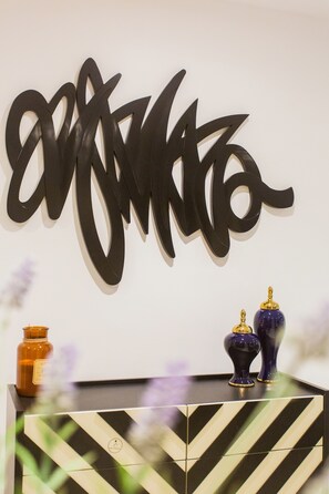 A wall with a large black abstract art piece and two decorative vases on a black and white patterned cabinet. - Comfy One Bedroom Apartment @ The Bantree (Accra)
