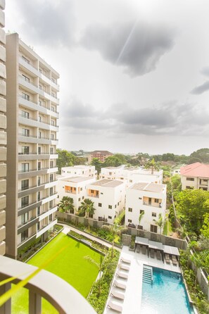 A high-rise hotel with multiple balconies, a swimming pool, and lush greenery. - Comfy One Bedroom Apartment @ The Bantree (Accra)
