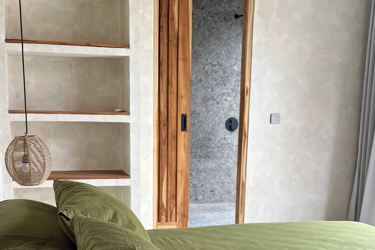 Un dormitorio con una cama, una puerta de madera y una estantería.