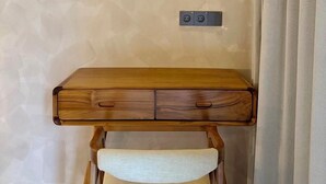 Een bureau in de hoek met een stoel, een stopcontact en een gordijn.