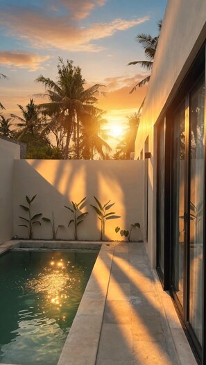 Piscina con vista sul tramonto, palme e facciata di un edificio moderno.