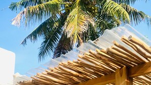An outdoor seating area with a wooden pergola, a sofa, and chairs. - Villa Canaria (Gili Trawangan)