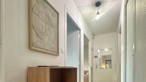 Un pasillo con un banco de madera, una obra de arte abstracta enmarcada y un aplique colgante.