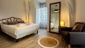 Un dormitorio con cama, sofá, espejo y lámpara colgante.