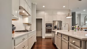 A modern kitchen with white cabinetry, stainless steel appliances, and a wooden floor. - 3-bedroom townhome in adorable Mableton. Close to all the charms of Atlanta. (Mableton)