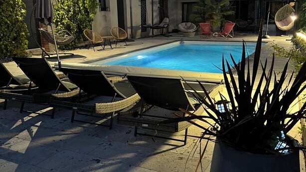 Una piscina con sillones de descanso y una planta en maceta al frente.