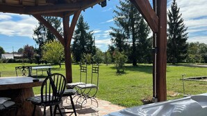 Un área de hidromasaje con un pérgola de madera, asientos exteriores y vistas a un campo cubierto de césped y árboles.
