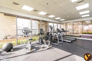 A gym with treadmills, elliptical machines, and exercise balls. - Vogue | Jeewar JVC near Circle Mall | Pool & Gym (Dubai)