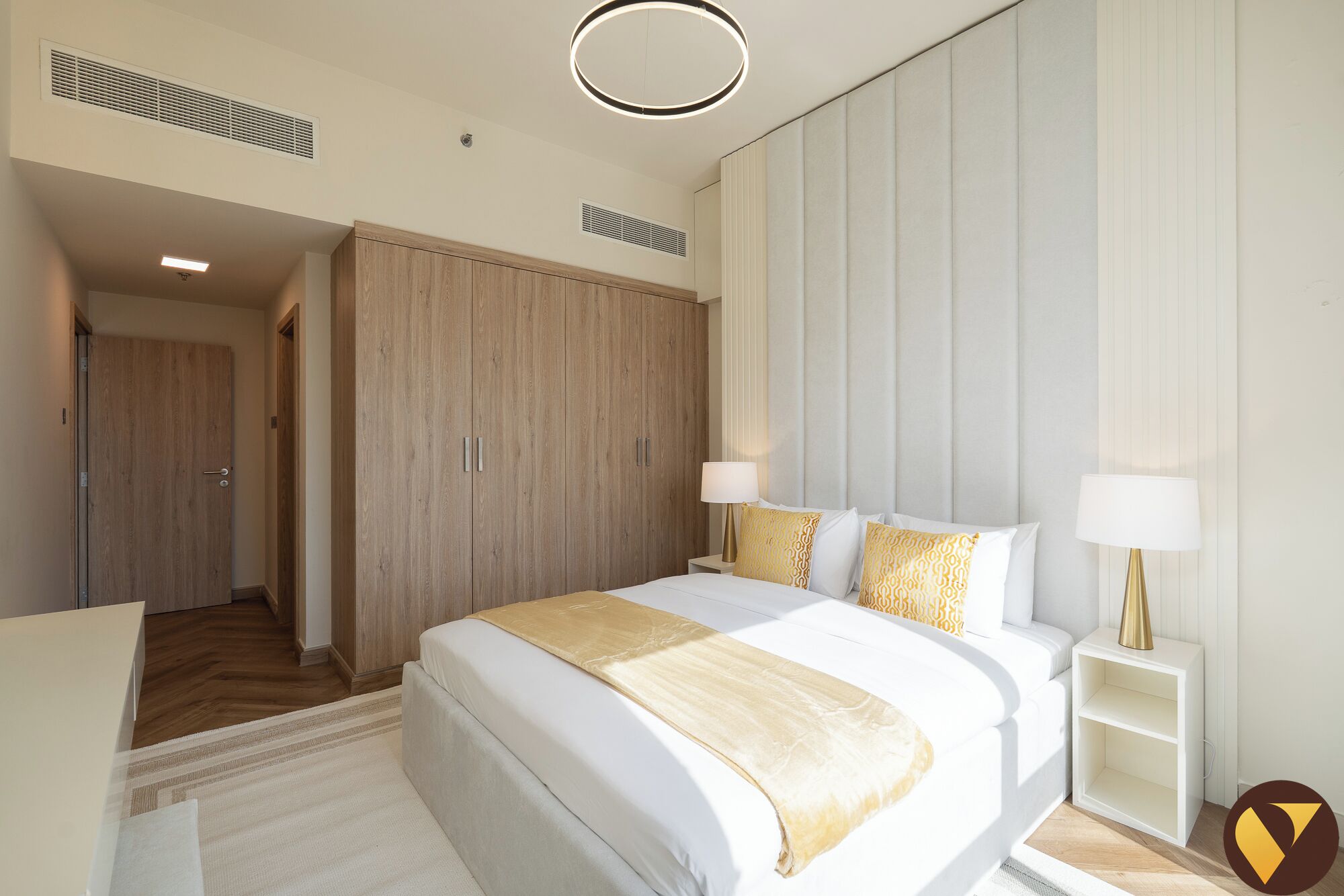 Une chambre d’hôtel moderne dotée d’un grand lit, de tables de chevet, d’une armoire et d’un dressing.