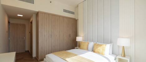 Une chambre d’hôtel moderne dotée d’un grand lit, de tables de chevet, d’une armoire et d’un dressing.