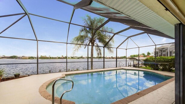 Piscina interna com vista para um lago e palmeiras.