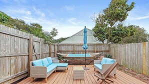 Eine Holzterrasse mit Korbmöbeln und einer Hängematte.