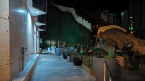 A nighttime view of a building's exterior with a staircase, potted plants, and a concrete pathway. - Samama Almaqam Hotel - Ajyad ( فندق سمامة المقام ) (Makkah)