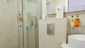 A modern bathroom with a glass-enclosed shower, a white toilet, a sink with a mirror, and toiletries on the wall. - Turquoise studio with AC in beautiful Budva perfect for getaway (Budva)