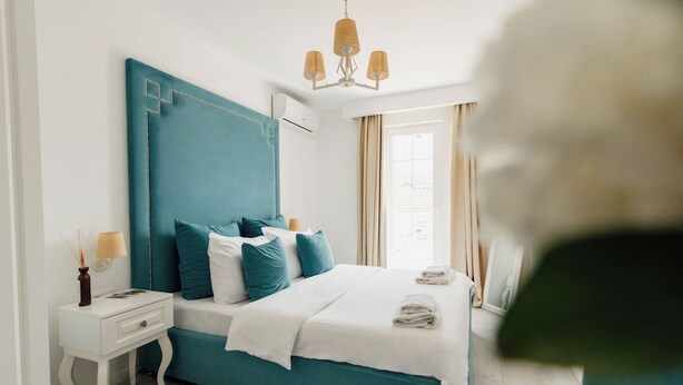 A modern bedroom with a teal headboard, white bedding, and a bedside table with a lamp. - Turquoise studio with AC in beautiful Budva perfect for getaway (Budva)