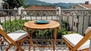 A balcony with a round wooden table and two white cushioned chairs. - Turquoise studio with AC in beautiful Budva perfect for getaway (Budva)