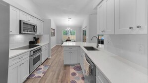 Una cocina moderna con armarios blancos, un microondas y un lavamanos.