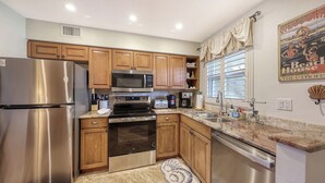 A kitchen with wooden cabinets, stainless steel appliances, a microwave, and a coffee maker. - Siesta Key - steps to the beach & pool#108 (Sarasota)