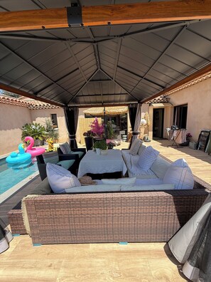A covered outdoor seating area with a pool, wicker furniture, and a thatched umbrella. - STUDIO swimming pool (Bouc-Bel-Air)