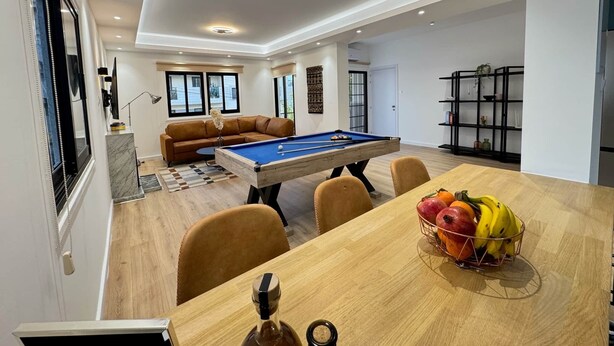 A modern living room with a pool table, a sofa, and a dining area with a fruit basket. - GameHouse in the City Center (Nicosia)