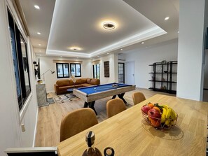 A modern living room with a pool table, a sofa, and a dining area with a fruit basket. - GameHouse in the City Center (Nicosia)