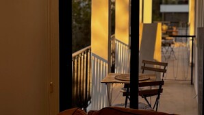 A balcony with a wooden table and chairs, a view of the outside, and a building in the background. - GameHouse in the City Center (Nicosia)