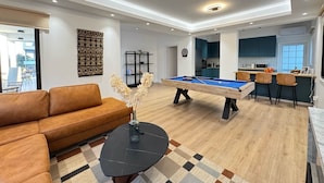 A modern living room with a pool table, a brown leather sofa, and a coffee table. - GameHouse in the City Center (Nicosia)
