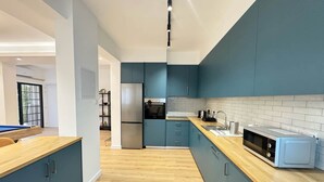 A modern kitchen with blue cabinets, a stainless steel refrigerator, and a microwave. - GameHouse in the City Center (Nicosia)
