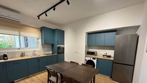 Eine moderne Küche mit türkis-blauen Schränken, einem Holztisch und einem Edelstahlkühlschrank.