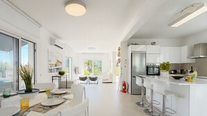 Eine moderne Küche mit weißen Schränken, einem Edelstahlkühlschrank und einer Bar mit Hockern.