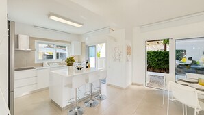 Eine moderne Küche mit Kochinsel, weißen Schränken und einem Essbereich mit Tisch und Stühlen.