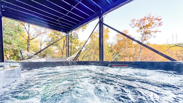 Un espace avec un bain à remous offrant une vue sur les arbres aux couleurs automnales.