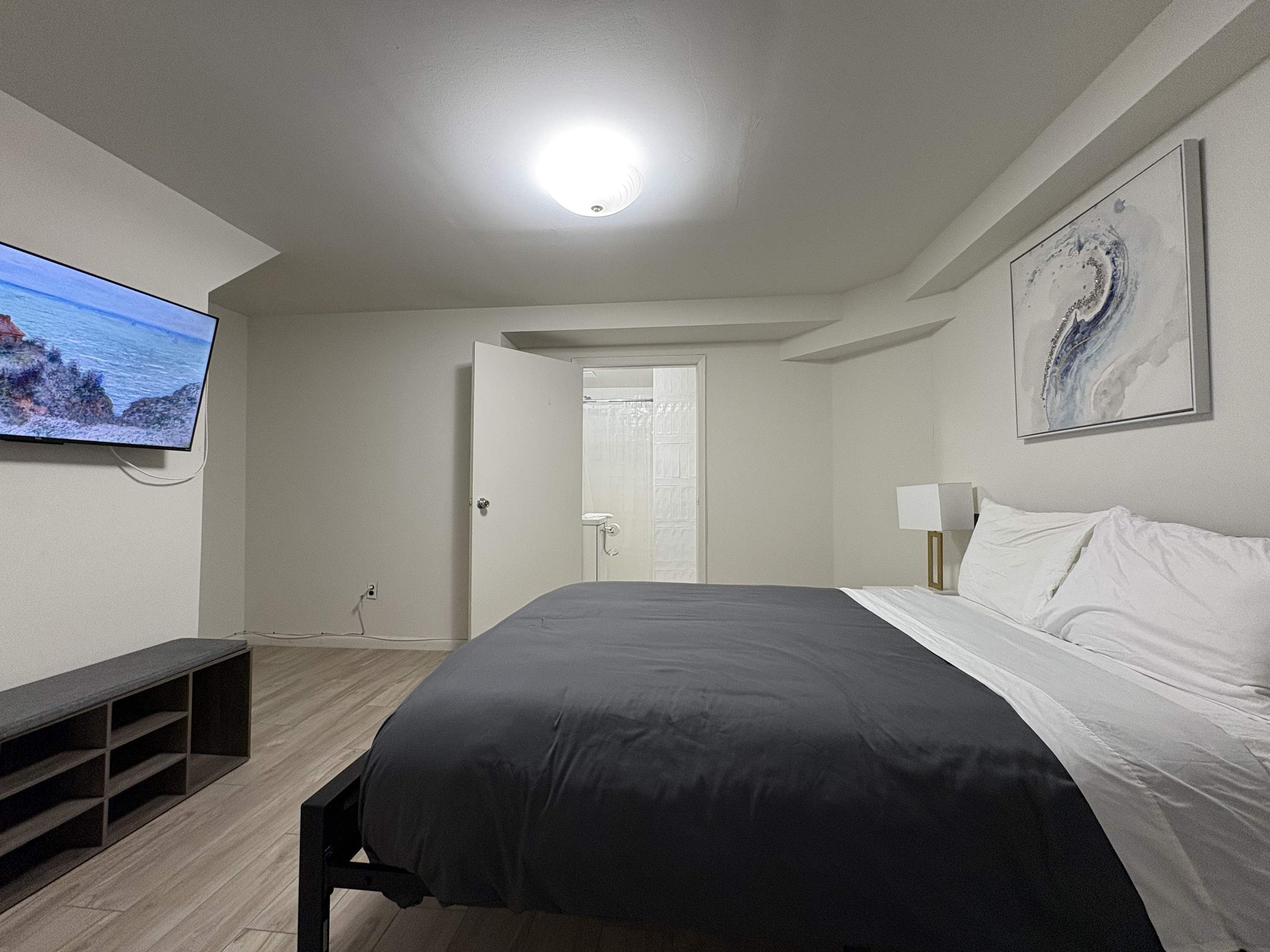 Ein Schlafzimmer mit einem Bett, einem Fernseher, einer Bank und einem Gemälde an der Wand.