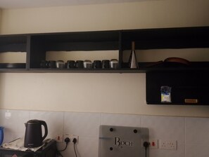 Una cocina con una cafetera Bosch, un hervidor y una estantería con tazas y un hervidor.