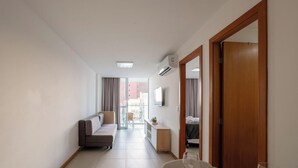 Ein modernes Hotelzimmer mit Sofa, Nachttisch, Spiegel und Blick ins Freie.