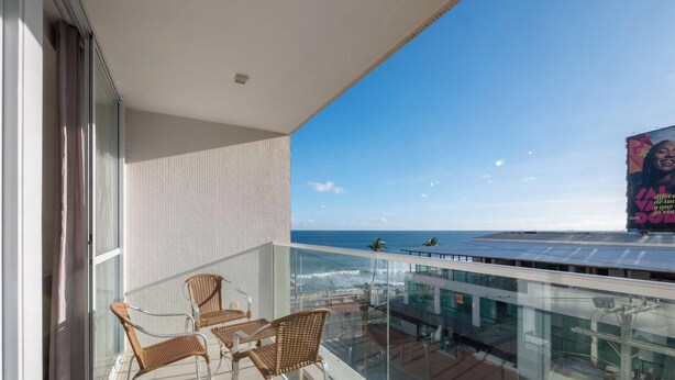 Ein Balkon mit Korbstühlen, einer Glastrennwand und Blick aufs Meer.