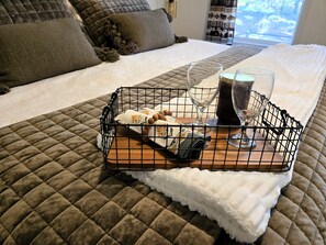A neatly made bed with a quilted brown bedspread, a white fluffy blanket, and a tray with a bottle, glasses, and a folded towel. - Adventure-Ready St. Germain Getaway Near Lakes, Trails & Rentals (Saint Germain)