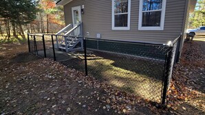 A house with a covered porch, a staircase, and a fenced yard. - Adventure-Ready St. Germain Getaway Near Lakes, Trails & Rentals (Saint Germain)