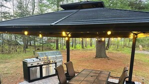 An outdoor patio with a grill, seating, and a pergola with string lights. - Adventure-Ready St. Germain Getaway Near Lakes, Trails & Rentals (Saint Germain)