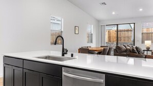 A modern kitchen with a large island, black cabinets, and a stainless steel dishwasher. - Private Bakersfield Getaway Near Downtown & Parks! (Bakersfield)