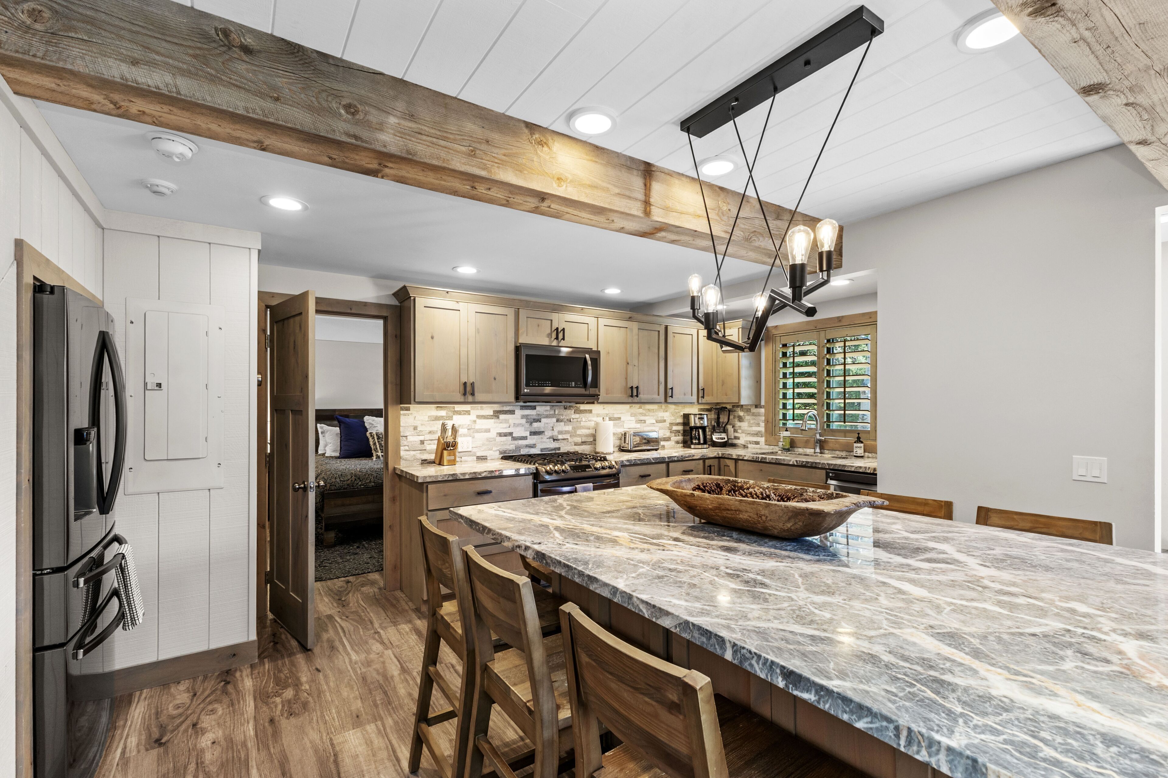 A modern kitchen with wooden cabinets, a marble island, and a built-in oven.