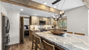 A modern kitchen with wooden cabinets, a marble island, and a built-in oven. - Creekside Retreat in the Heart of Sun Valley! (Sun Valley)