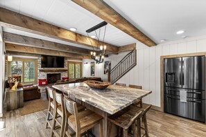 Eine Küche mit einer Marmorinsel, Holzstühlen, einem Edelstahlkühlschrank und einem Kamin aus Stein.
