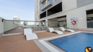 A rooftop pool area with lounge chairs and a swimming pool. - Vogue | Jeewar By Badr JVC near Circle Mall (Dubai)