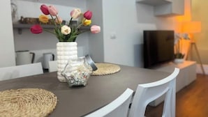 A modern dining area with a round table, white chairs, a vase of tulips, and a glass jar with a metal lid. - A Casa di Imma - Elegant studio apartment in Porta Rom (Milano)