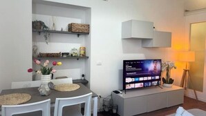 A modern living room with a dining area, a flat-screen TV, and a white console table. - A Casa di Imma - Elegant studio apartment in Porta Rom (Milano)