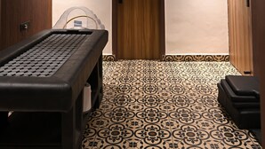 Ein Korridor mit Deckenventilator, gemusterten Bodenfliesen, einer Tür und einem kleinen Tisch mit Tastatur.