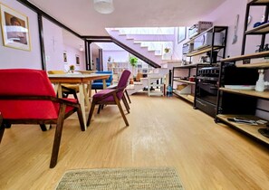 A modern kitchen with wooden flooring, a dining area with a table and chairs, and a staircase leading to an upper level.